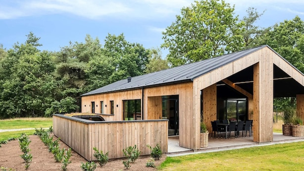 Una cabaña moderna de madera con un porche cubierto y una pequeña cocina al aire libre.