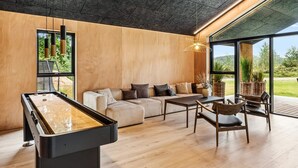 Una sala moderna con mesa de billar, sofá y comedor.