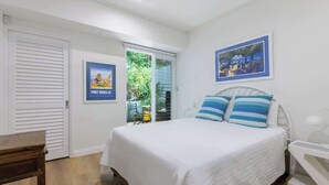 A bedroom with a bed, a window, a door, and a poster on the wall. - Villa 5 on Murphy - Spacious Living, Walk to Town (Port Douglas)
