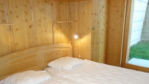 A wooden-paneled room with a bed, a bedside lamp, and a window. - Charming Apartment With Valley View (Veysonnaz)