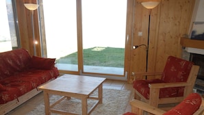 A cozy living room with a wooden floor, a red sofa, a wooden armchair, and a small table. - Charming Apartment With Valley View (Veysonnaz)