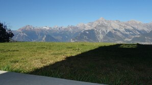 A grassy field with a mountain range in the background. - Charming Apartment With Valley View (Veysonnaz)