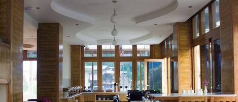 A spacious restaurant with high ceilings, wooden beams, and large windows.