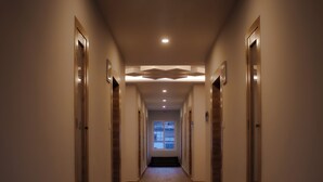 A long, narrow hallway with wooden flooring and recessed lighting. - Hotel Bhutan Home Thimphu (Thimphu)
