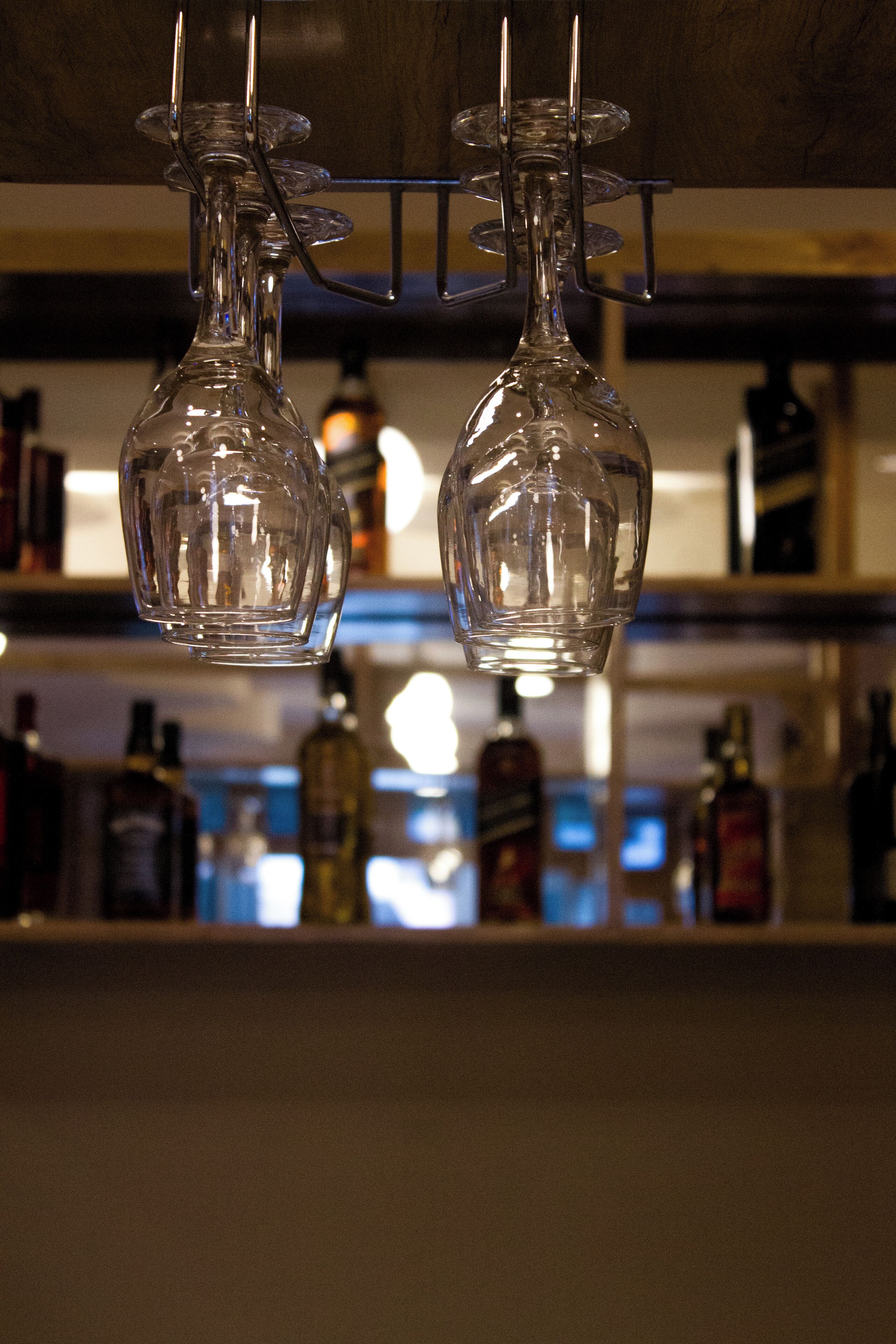 Two clear glass decanters hanging from a rack.