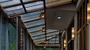 A spacious corridor with a glass ceiling, wooden partitions, and potted plants. - Hotel Bhutan Home Thimphu (Thimphu)
