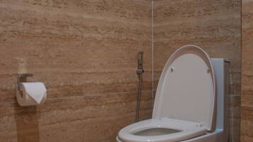 Une salle de bain avec un mur en marbre, des toilettes, un porte-serviettes et un support à papier toilette.