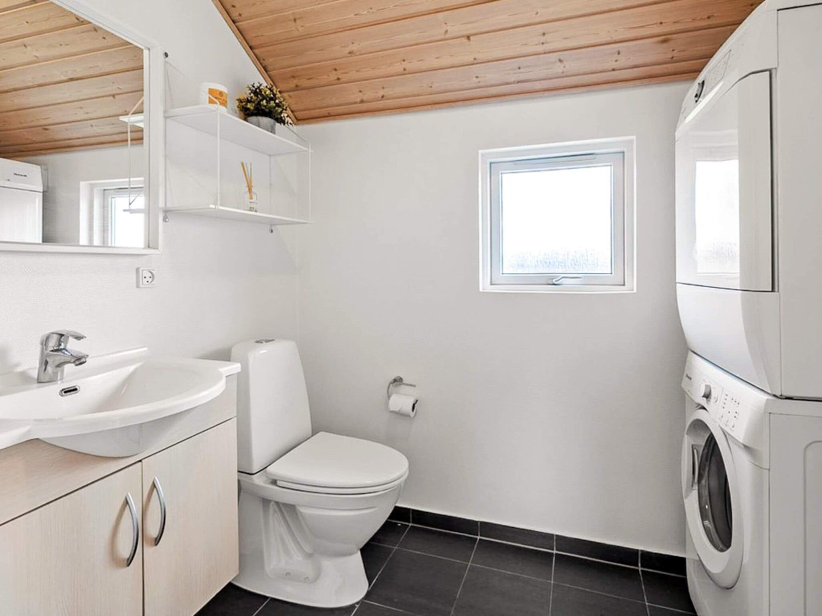 A compact bathroom with a sink, toilet, and washing machine.