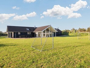 A residential property with a large house, a covered patio, and a grassy yard with a swing set.
