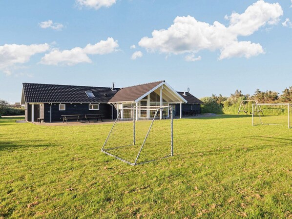A residential property with a large house, a covered patio, and a soccer goal in a grassy yard.