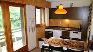 Une cuisine de taille réduite, dotée de meubles en bois, d’une cuisinière et d’un évier. On y trouve une table à manger avec des chaises et un tapis.