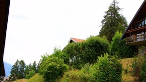 Une colline avec un chalet en bois et un mur de pierres.
