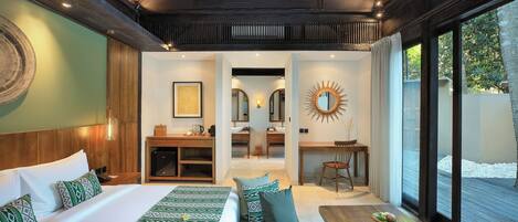 A modern hotel room with a large bed, a sofa, a dining table, and a view of the outdoors.