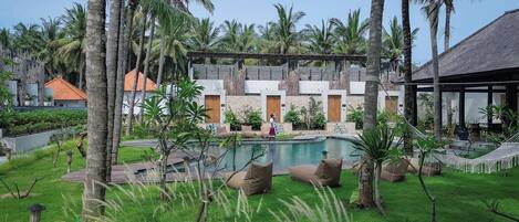 A resort with a swimming pool, palm trees, and a building with multiple rooms.