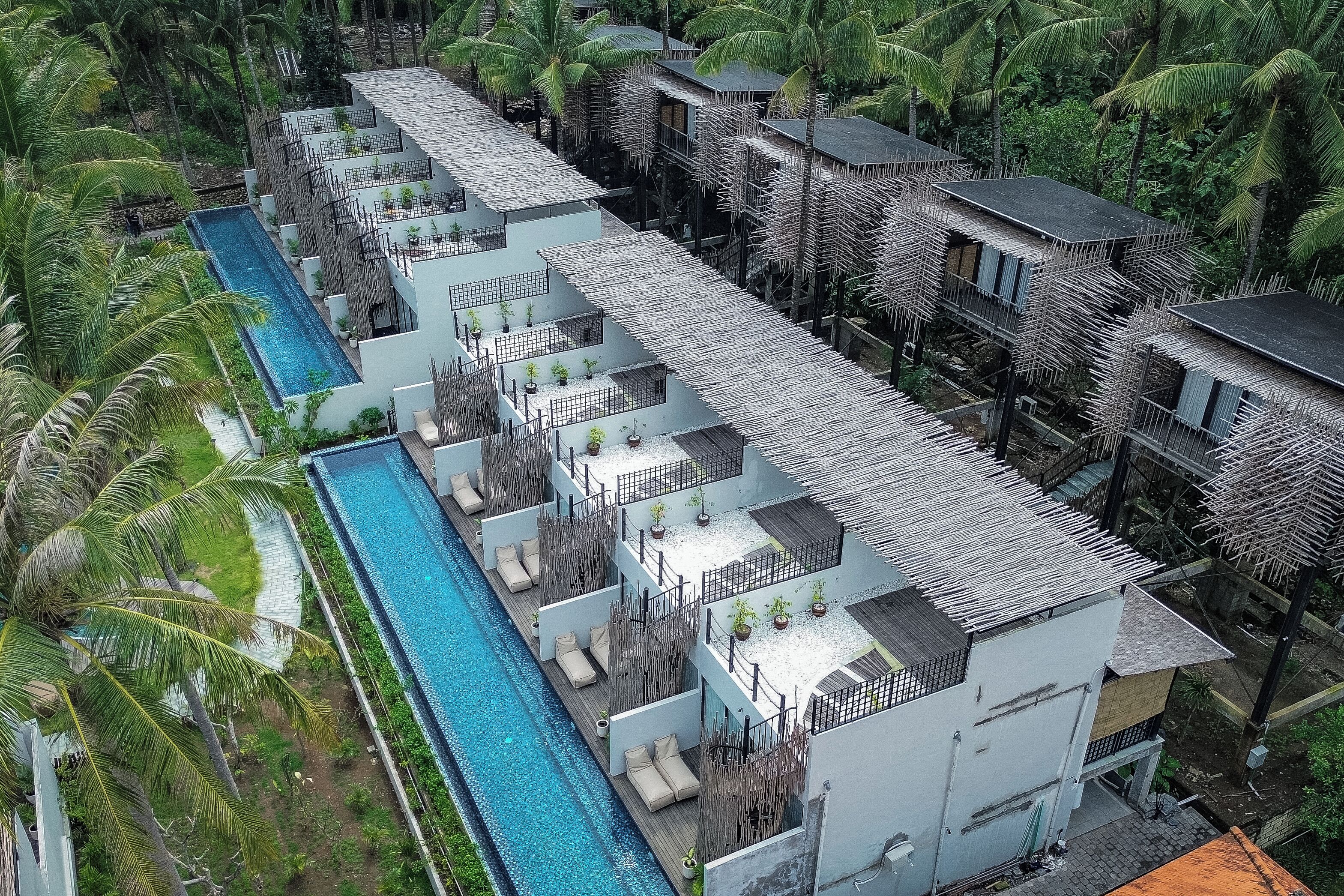 Un resort con varias edificaciones, piscina y abundante vegetación.