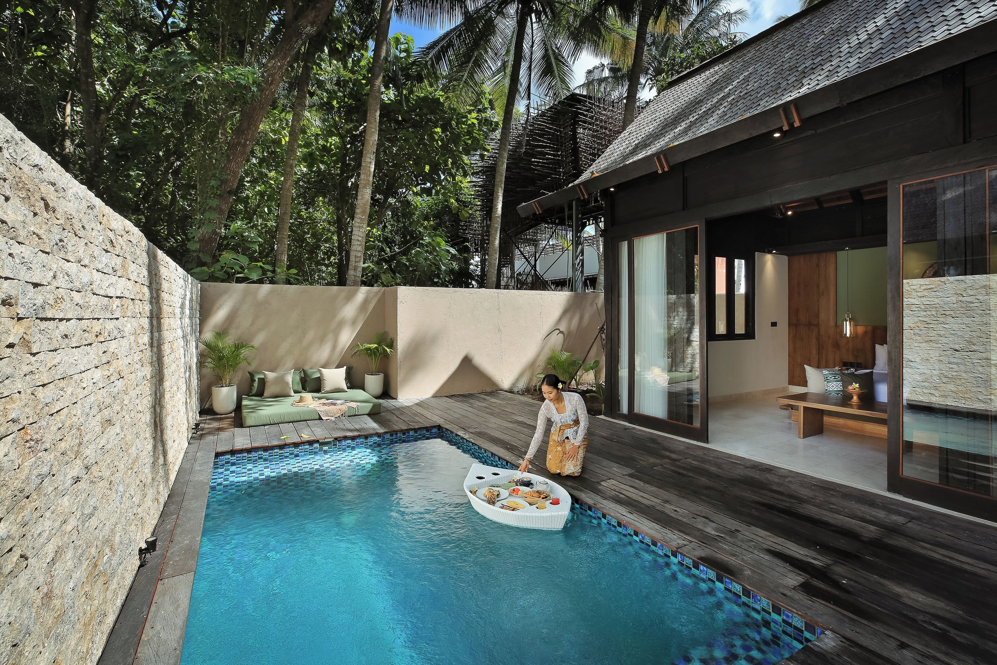 A swimming pool with a boat, surrounded by a wooden deck and a stone wall.