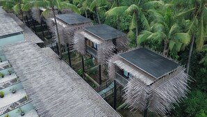 A series of elevated bamboo structures with thatched roofs, surrounded by dense palm trees. - The Sebali Penida Beach Resort (Penida Island)