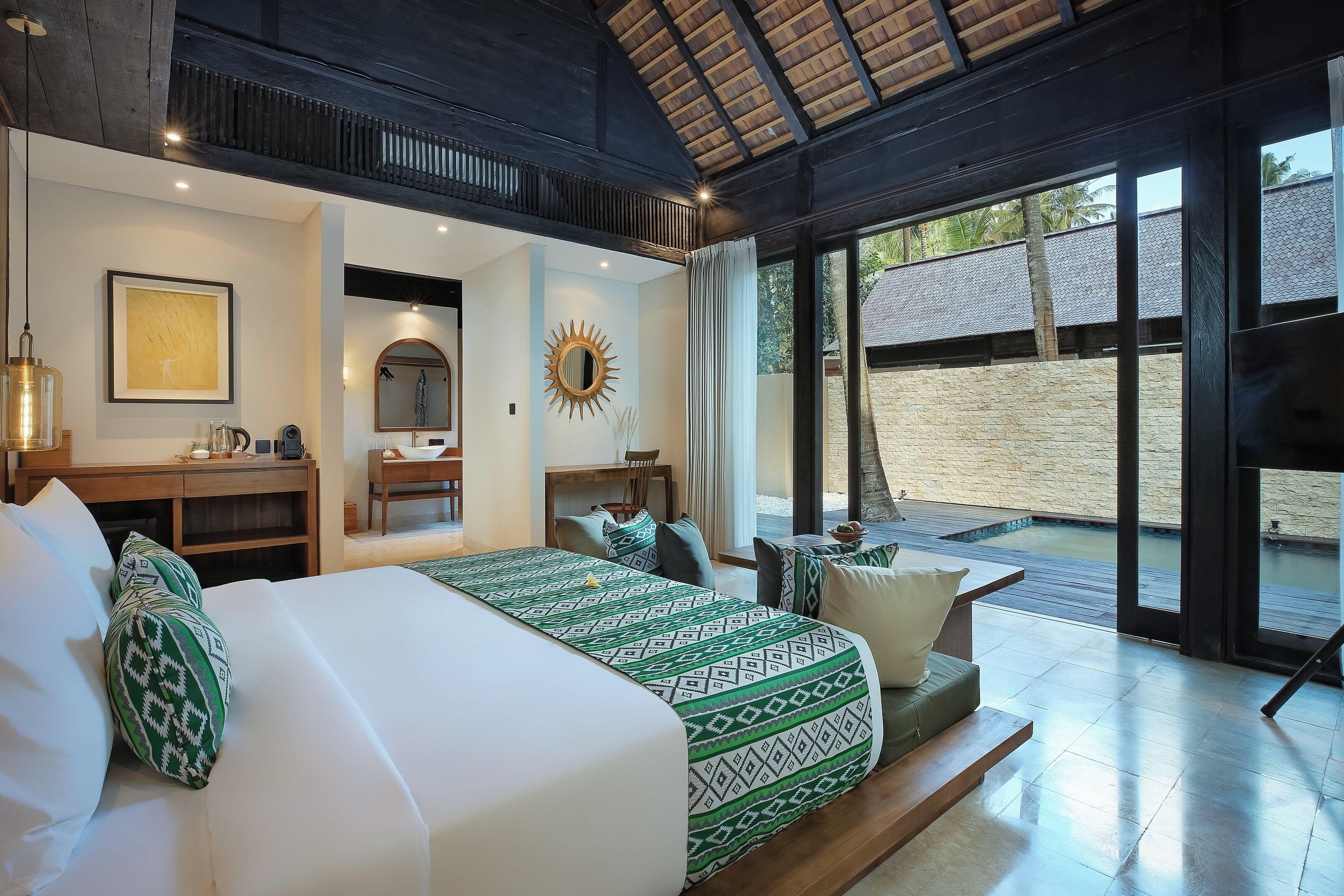A spacious bedroom with a large bed, a desk, and a view of the outdoors.