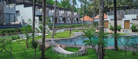 A resort with a swimming pool, hammock, and lush greenery.