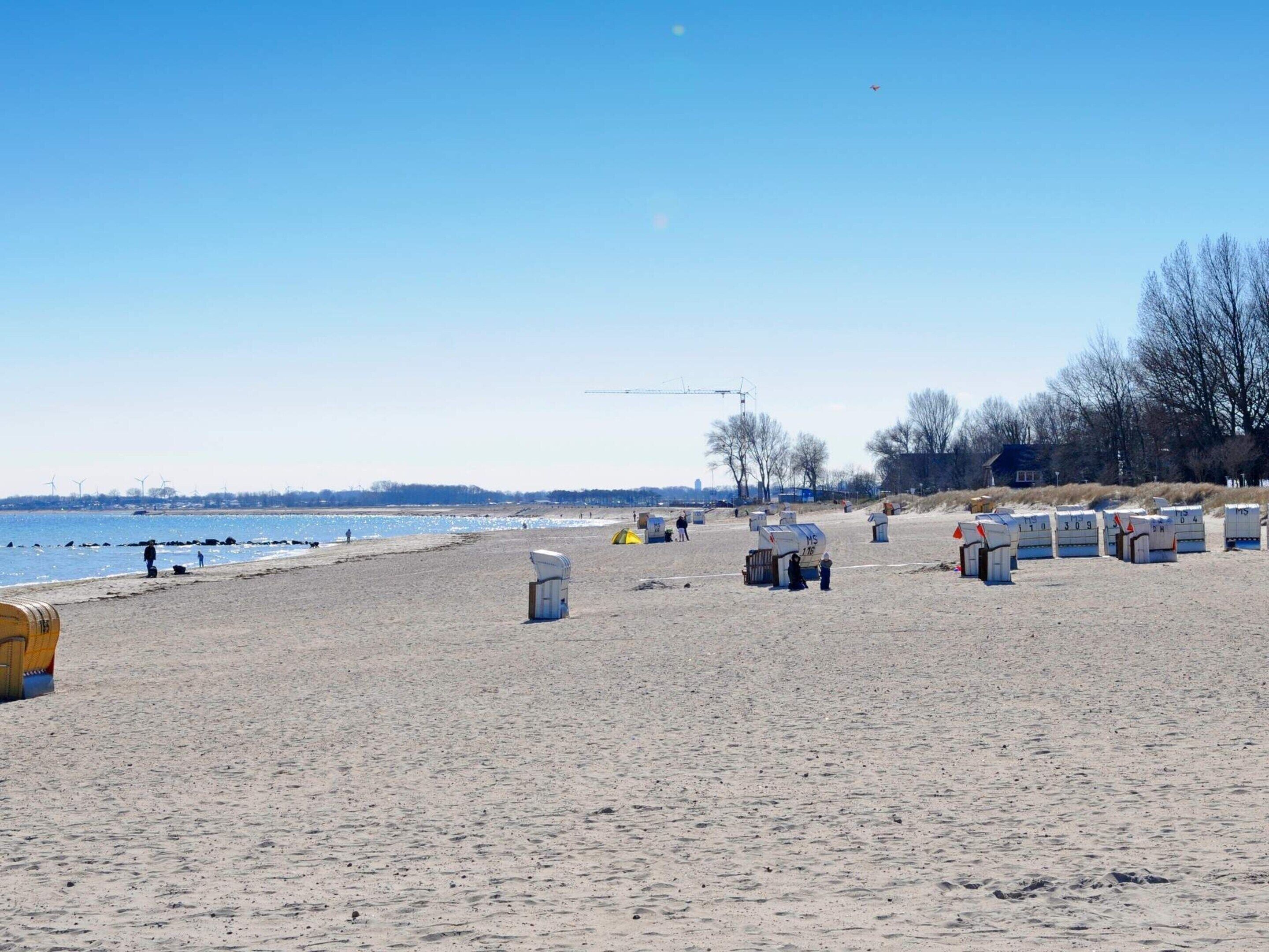 A beach with sand, a body of water, and a few people.
