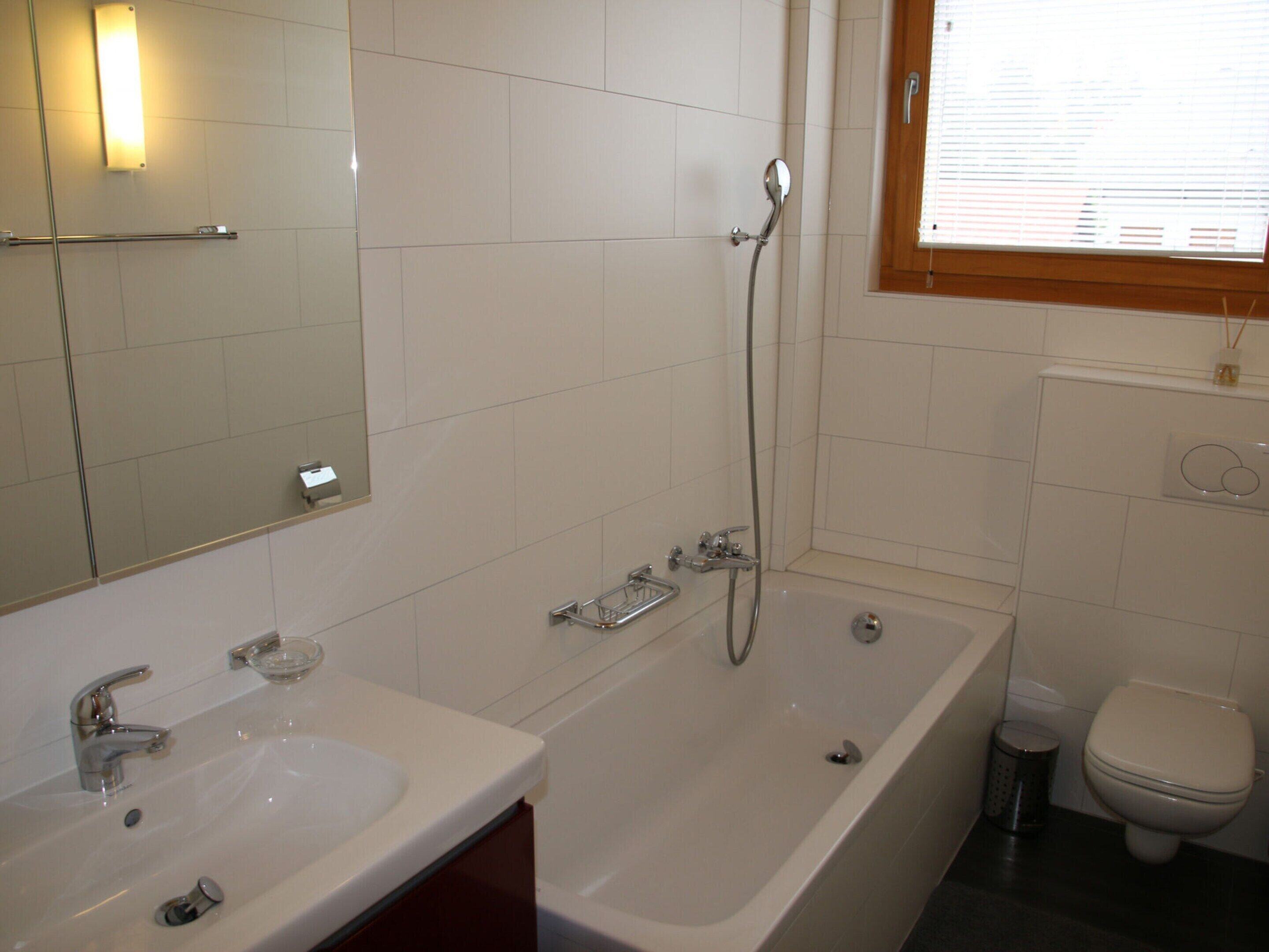 A bathroom with a bathtub, a sink, a toilet, and a mirror.