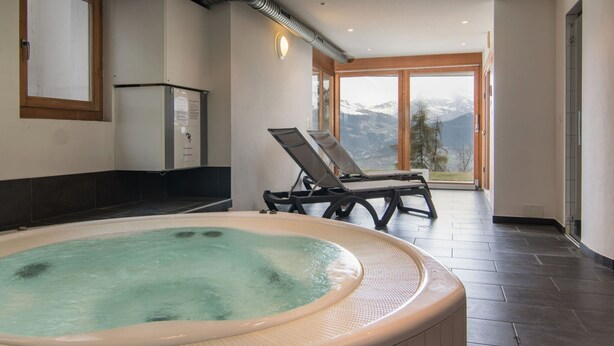 A spa area with a hot tub, a window with a mountain view, and a sauna. - Hilltop Apartment With Valley Views (Veysonnaz)