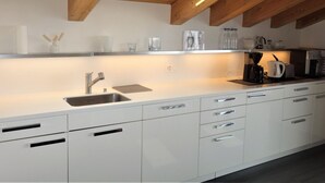 A modern kitchen with white cabinets, a stainless steel sink, and wooden beams on the ceiling. - Hilltop Apartment With Valley Views (Veysonnaz)
