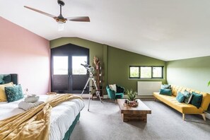 A bedroom with a bed, a desk, a chair, a sofa, and a ceiling fan. - Large barn with hot-tub in the English countryside

 (Oakham)