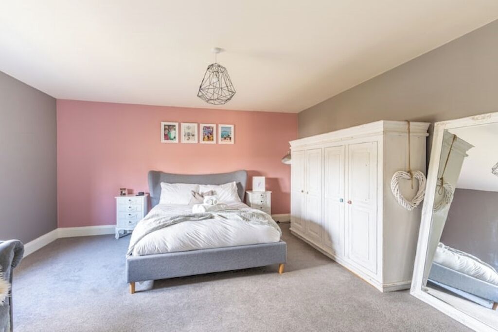 A bedroom with a bed, nightstands, a wardrobe, and a mirror.