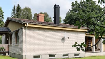 Un edificio de ladrillo con chimenea, antena parabólica y ventanas pequeñas.