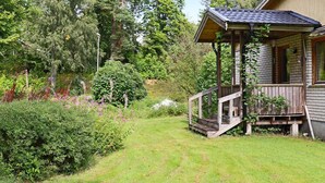 A wooden cabin with a porch, surrounded by lush greenery and trees. - 4 Star Holiday Home in Unnaryd (Unnaryd)