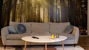 Een woonkamer met een grijze bank, twee kussens, een witte salontafel en een vloerkleed.