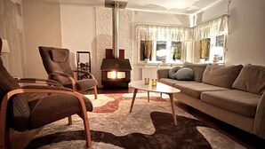 Een gezellige woonkamer met een open haard, een bank, twee fauteuils en een salontafel.