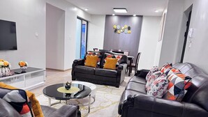 A modern living room with leather sofas, a coffee table, and a TV mounted on the wall.
