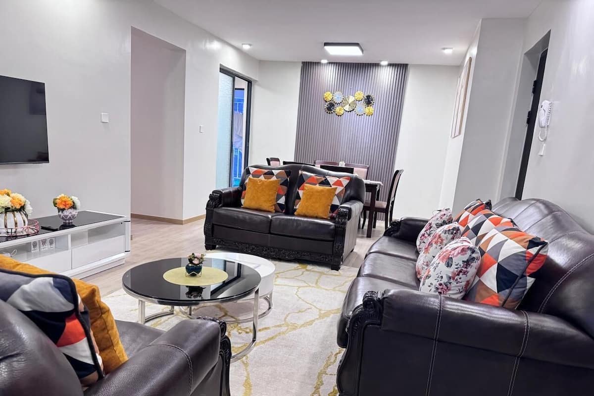 A modern living room with leather sofas, a coffee table, and a TV mounted on the wall.