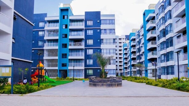 A modern apartment complex with multiple high-rise buildings, a central courtyard with greenery, and a playground area.