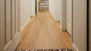 Un couloir avec un paillasson menant à une cuisine.