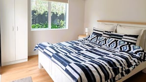 Une chambre à coucher avec un lit, une table de chevet, une fenêtre et une armoire.
