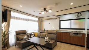 A modern living room with a sofa, a coffee table, and a kitchen area with a dishwasher. - HARRISON (Sapporo)