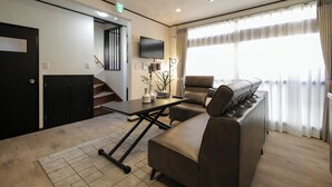 A modern living room with a sofa, a coffee table, and a TV mounted on the wall. - HARRISON (Sapporo)
