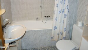 Un baño con bañera, lavamanos e inodoro.