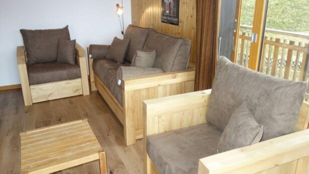 Una habitación acogedora con piso de madera, dos sofás y una pequeña mesa de madera.