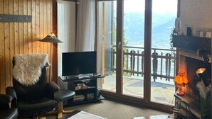 Una sala de estar acogedora con un televisor grande, chimenea y vistas a las montañas.