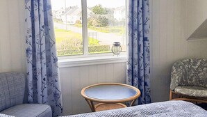 Une pièce avec une fenêtre, une petite table ronde et deux chaises.