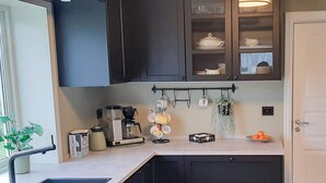 Une cuisine moderne avec des meubles de couleur sombre, une machine à café et un porte-tasses suspendu.