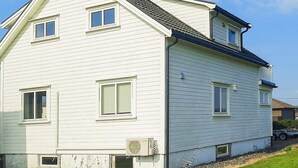 Une maison à deux étages, dotée d’un toit à pignon, de nombreuses fenêtres et d’un appareil de climatisation.