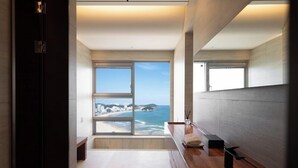 A modern hotel room with a large window offering a view of the beach and ocean.