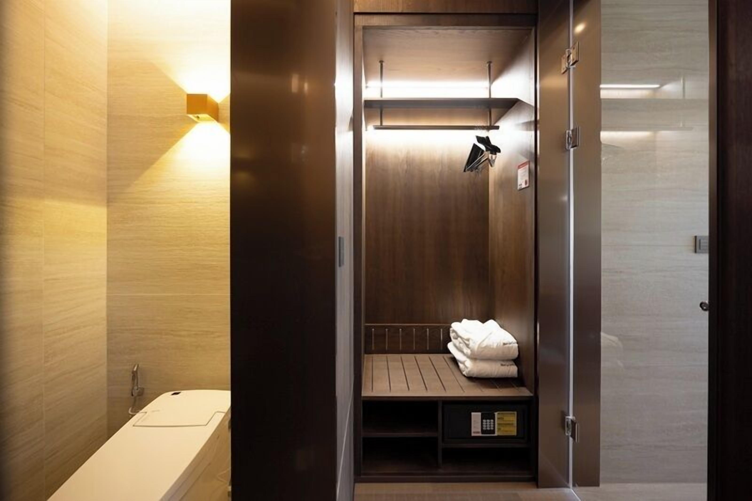 A modern bathroom with a built-in shower, a towel rack, and a control panel.