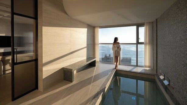 A modern interior with a pool, large windows, and a view of the sea.