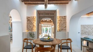 A dining area with a round wooden table, four wicker chairs, and stone walls. - Impressive Farmhouse With Pool (Santa Eulalia del Rio)